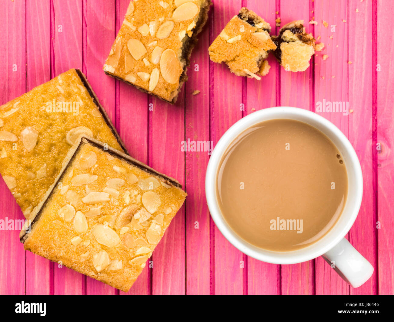 Kirsche Bakewell-Törtchen mit eine Tasse oder einen Becher Tee oder Kaffee vor einem rosa Hintergrund Stockfoto