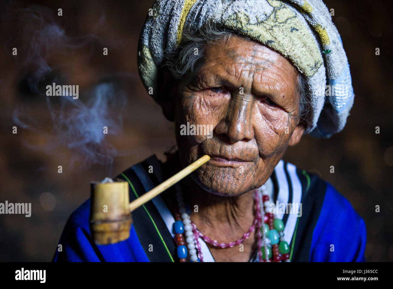 Kinnbereich, Myanmar, 11. November 2014: Muun Stamm Kinn Dame in ihrer Küche, ihre Pfeife rauchen Stockfoto