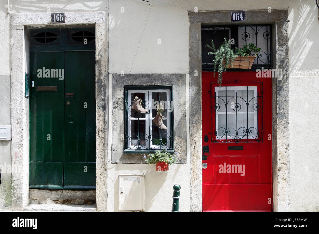 Vordere Türen in zwei nebeneinander liegende Häuser, zahlen 164 & 166, eine rote, eine grüne mit einem kleinen Fenster zwischen ihnen mit zwei Stiefel als Pflanzer. Stockfoto