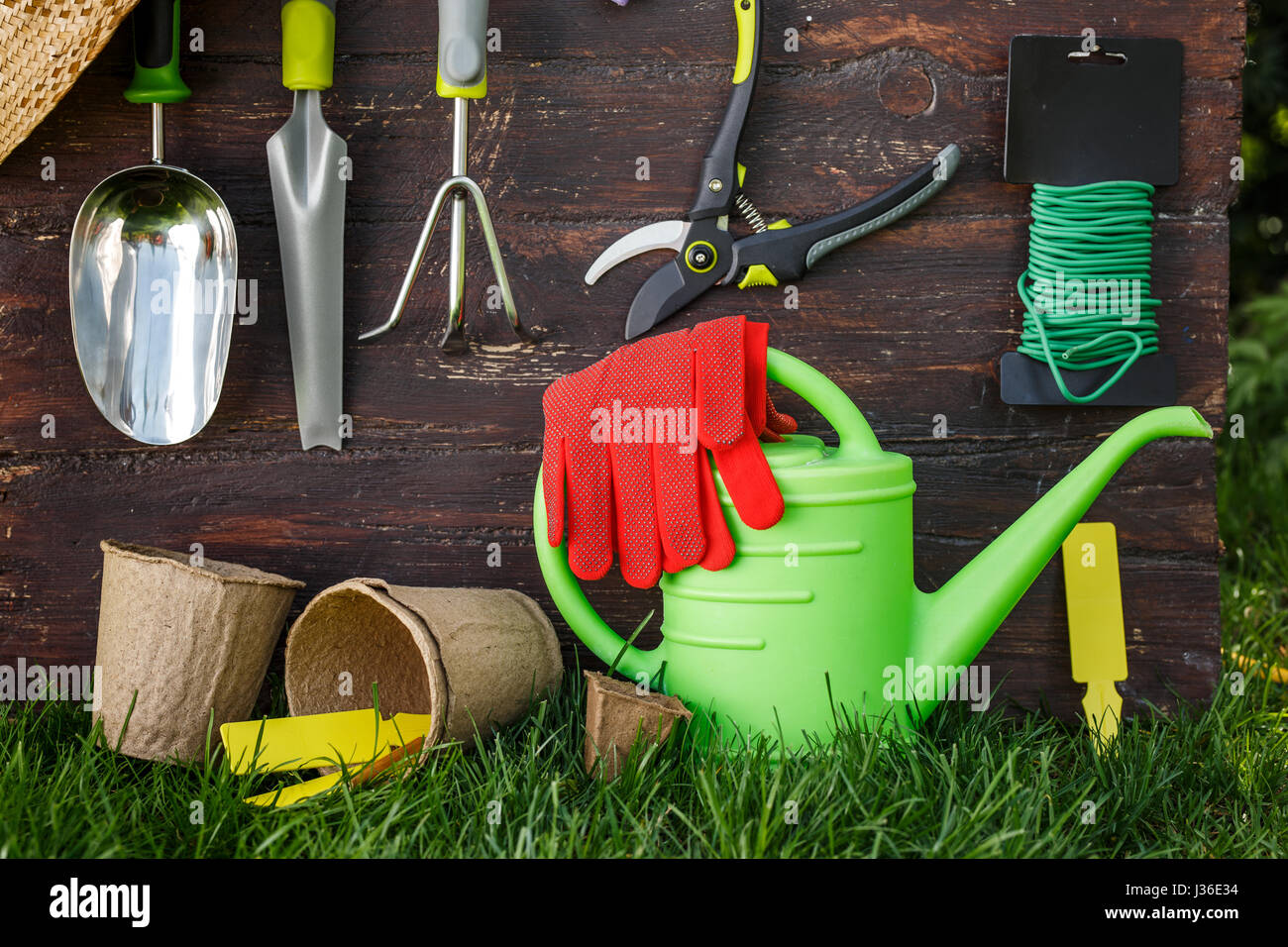 Gartengeräte und einen Strohhut auf dem Rasen im Garten. Stockfoto