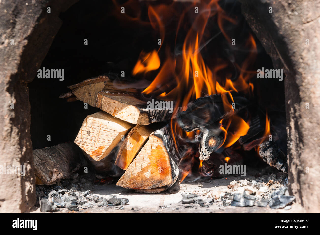 Brennholz in einem Vintage Ton Brennen Ofen. Feuer und ein Hauch von Rauch  über das verbrannte Holz Stockfotografie - Alamy