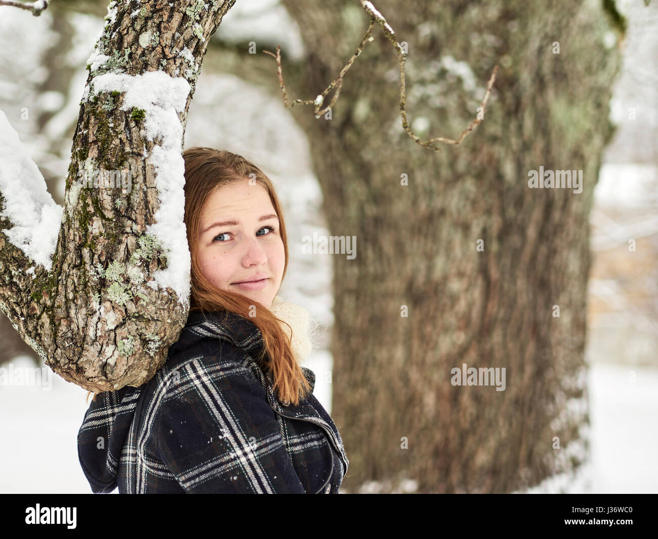 Schöne junge Mädchen tragen einen Wintermantel und sie sieht in Richtung Kamera, finnische Wintertag im Februar Stockfoto