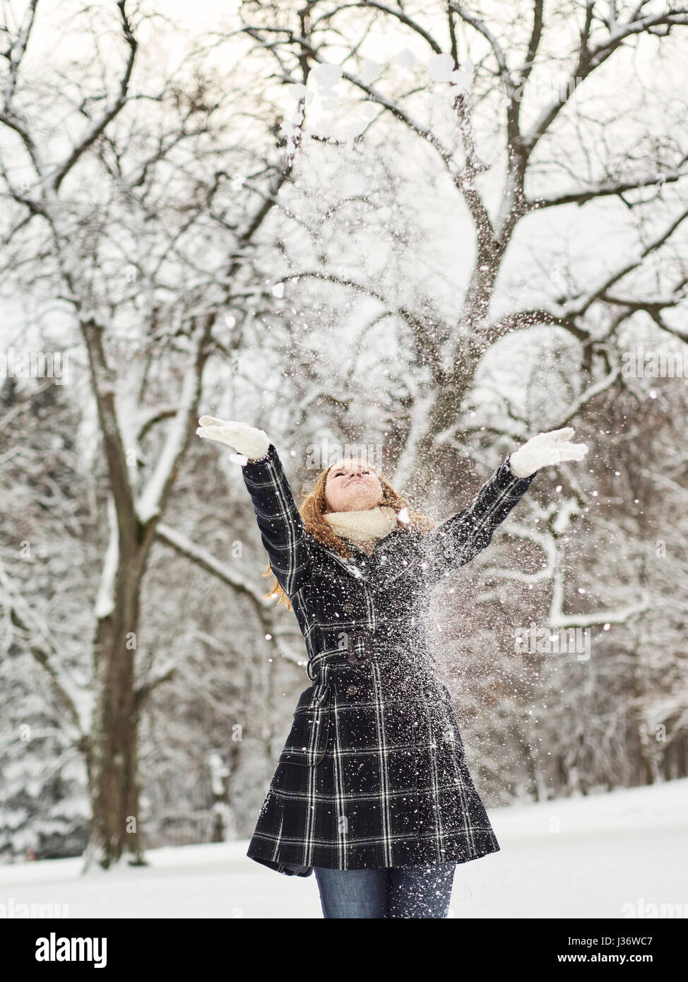 Schöne junge Mädchen tragen einen Wintermantel und kotzte Schnee in der Luft, Finnisch Wintertag im Februar Stockfoto