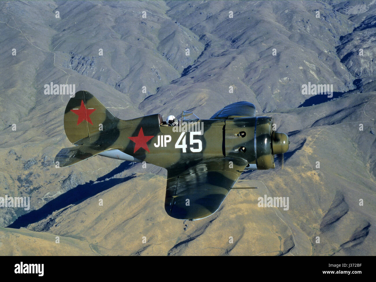 Pilot ist winken und fliegt eine seltene sowjetische Fighterplane von WW II Polikarpow i-16 Rata fliegen über den südlichen Alpen in Neuseeland Stockfoto