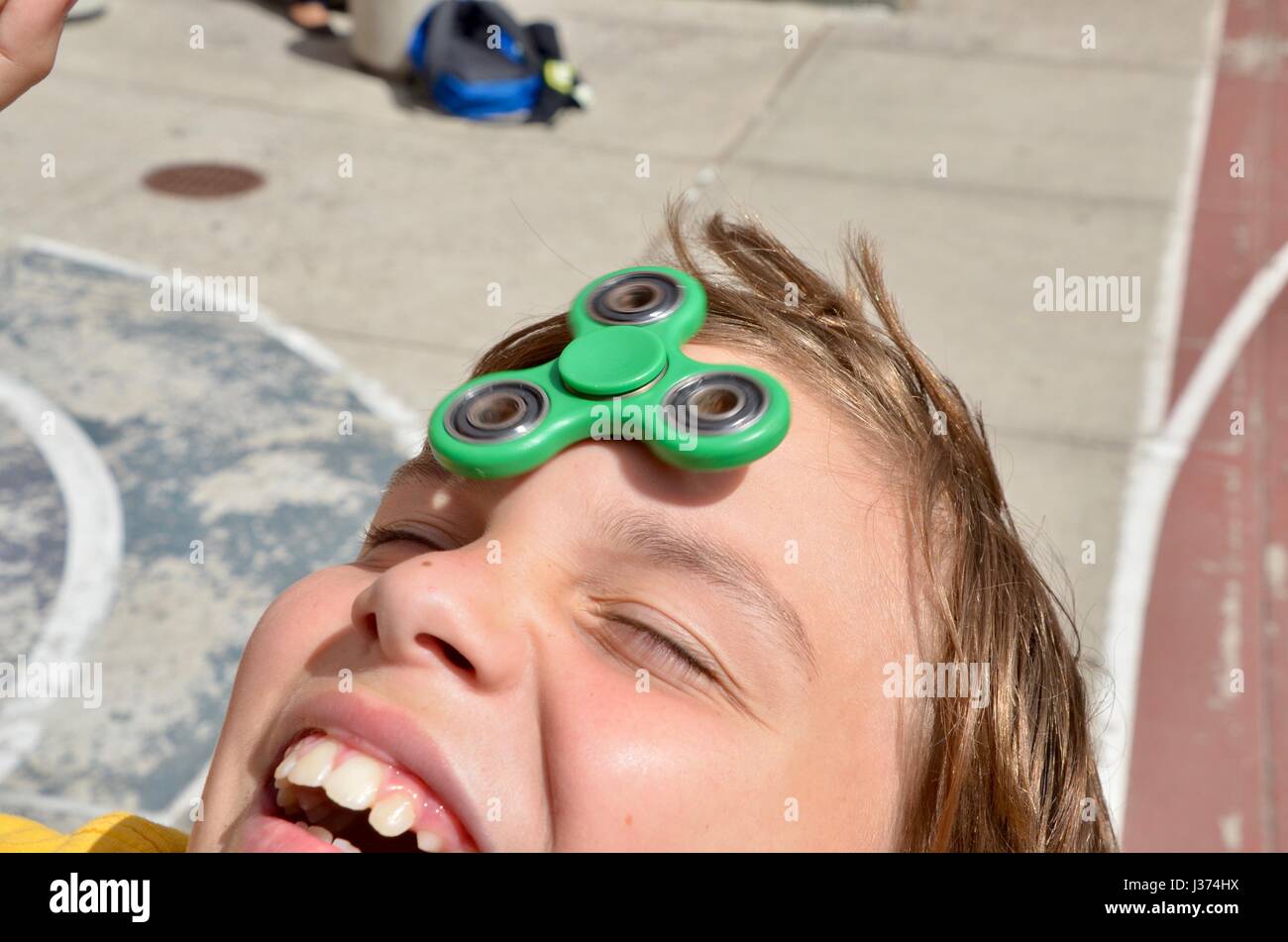 Ein Junge spielt mit einem grünen Fidget Spinner in Brooklyn New York USA Stockfoto