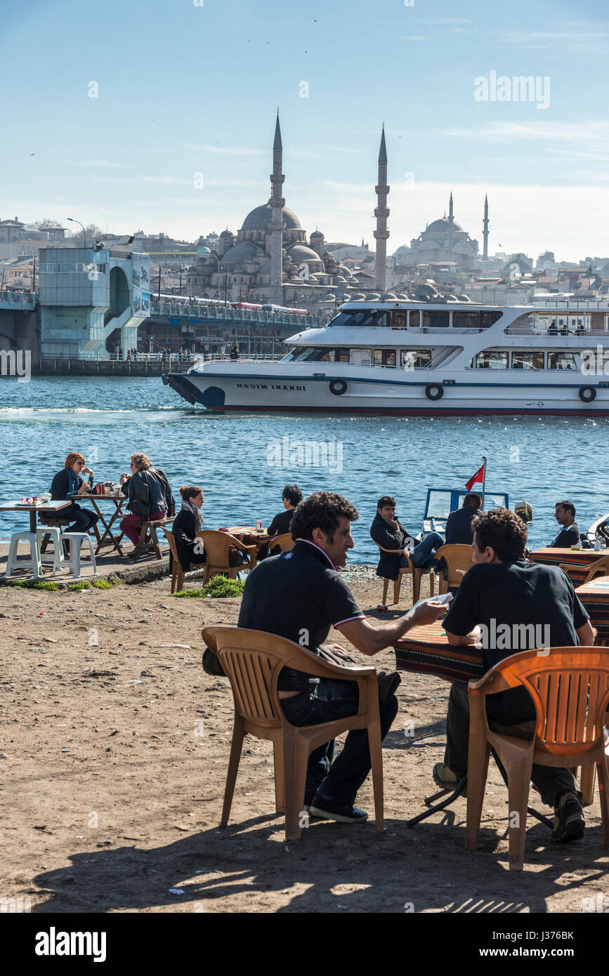 Cafe am Karakoy Waterfront, Blick über das Goldene Horn auf die Yeni-Moschee auf Eminönü und die Skyline von Istanbul. Istanbul, Türkei. Stockfoto