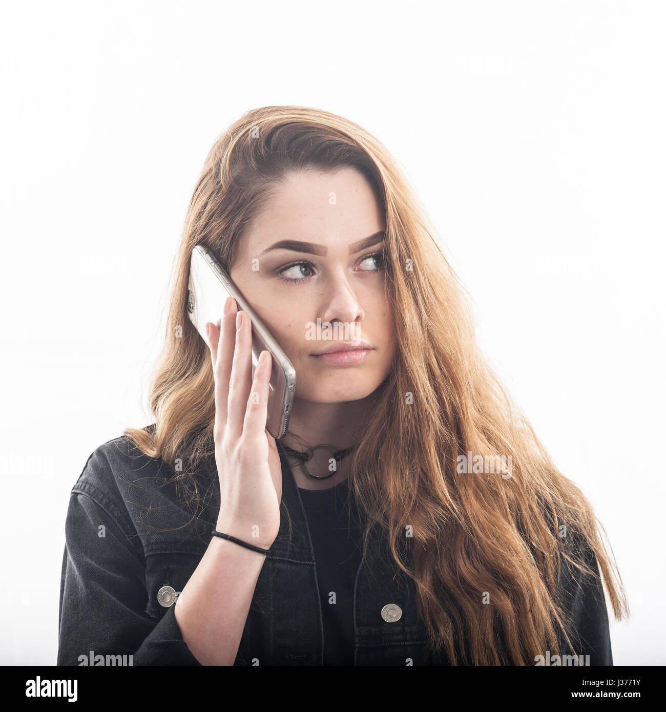 Ein ziemlich 15 Jahre altes Mädchen am Smartphone im Studio vor einem weißen Hintergrund im Vereinigten Königreich Stockfoto