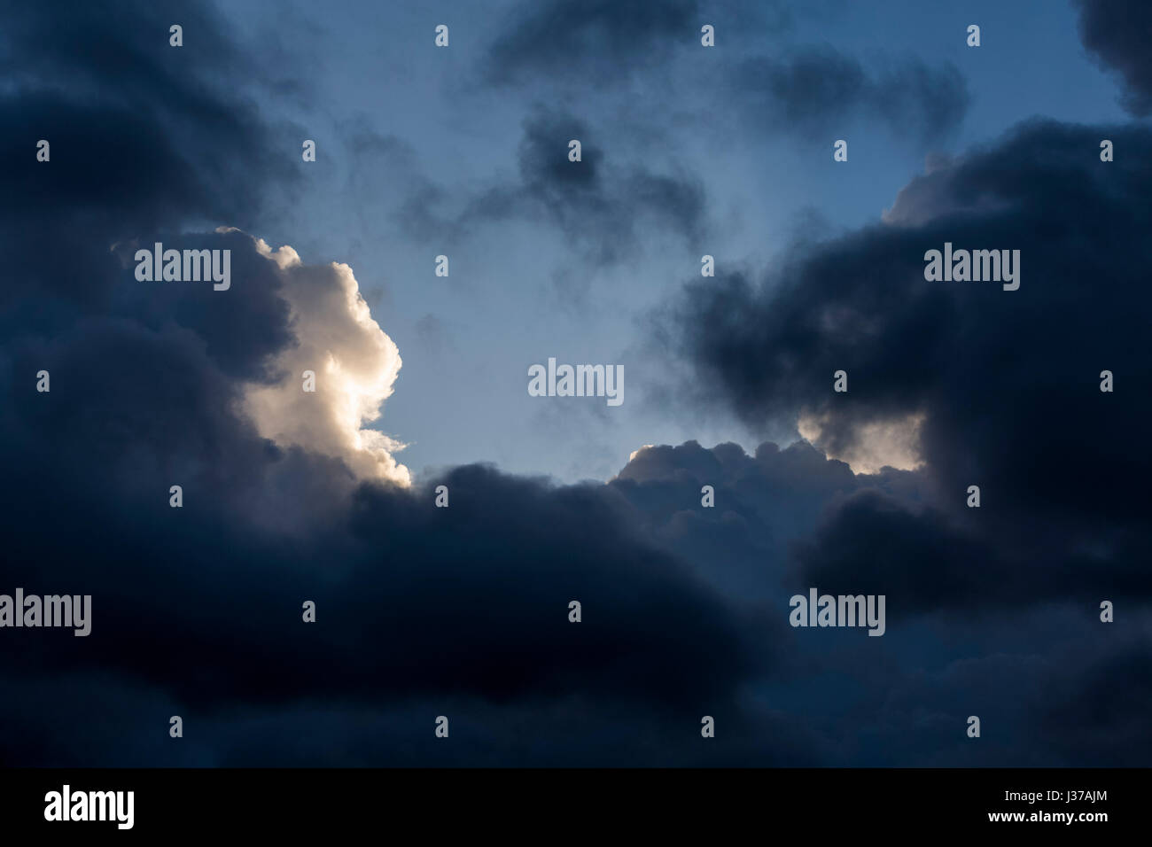 Gewitterwolken im Morgengrauen mit Sonne trifft eine Wolke, die hinter den dunklen Wolken hervorheben Stockfoto