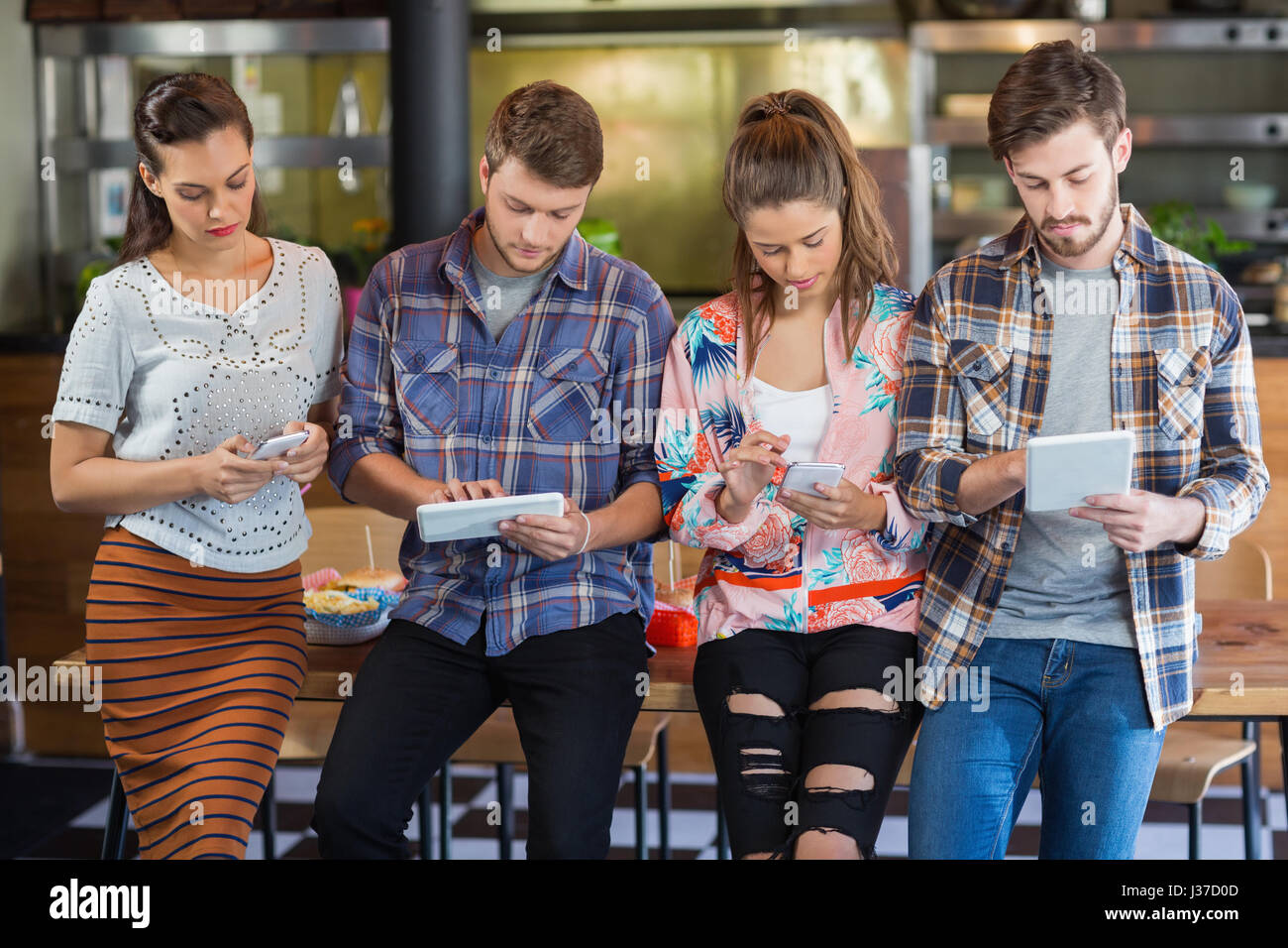 Freunde mit Handys und digitalen Tablets stehen im restaurant Stockfoto