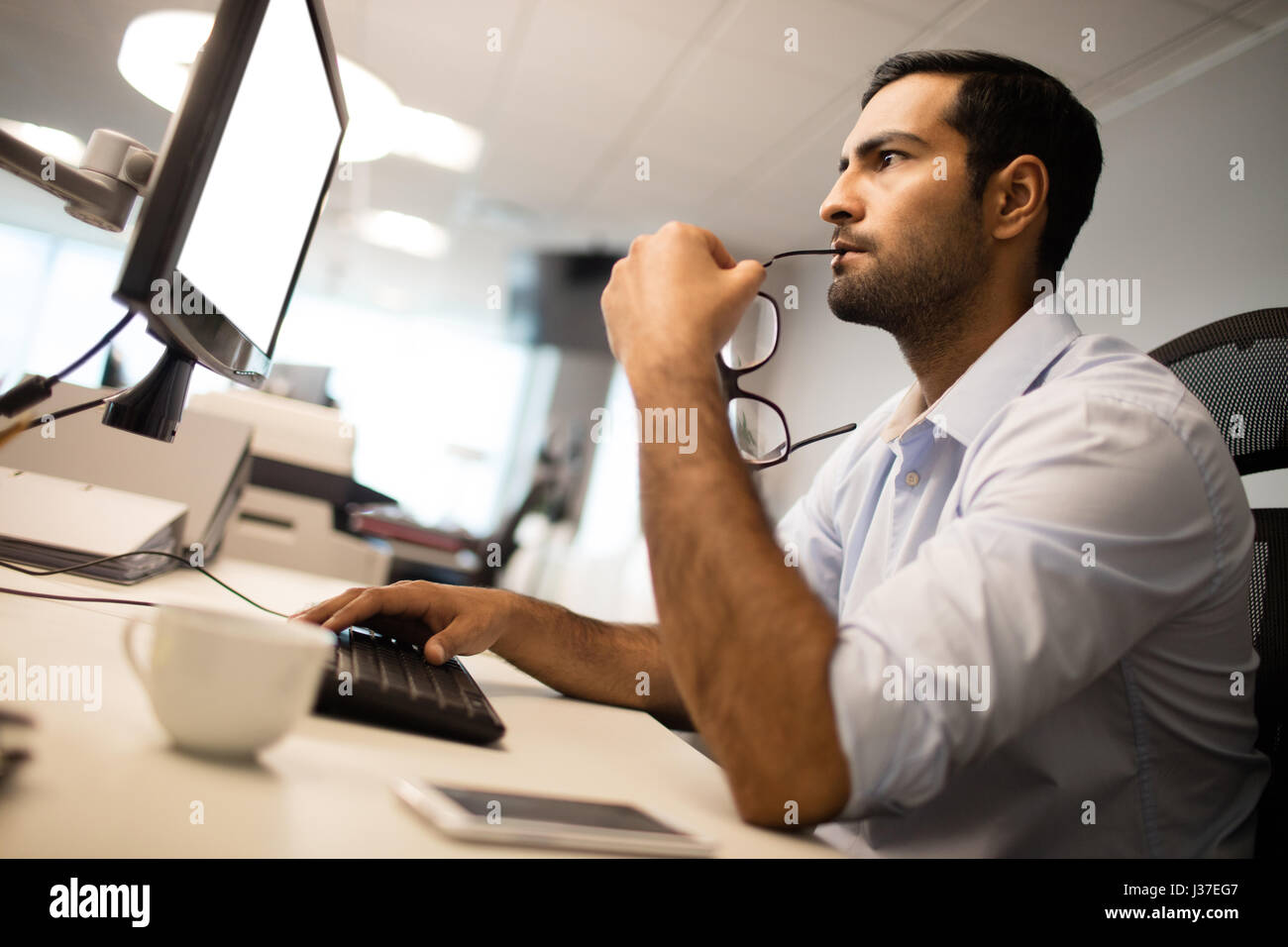 Tilt-Bild des nachdenklichen Geschäftsmann mit Computer am Schreibtisch im Büro Stockfoto