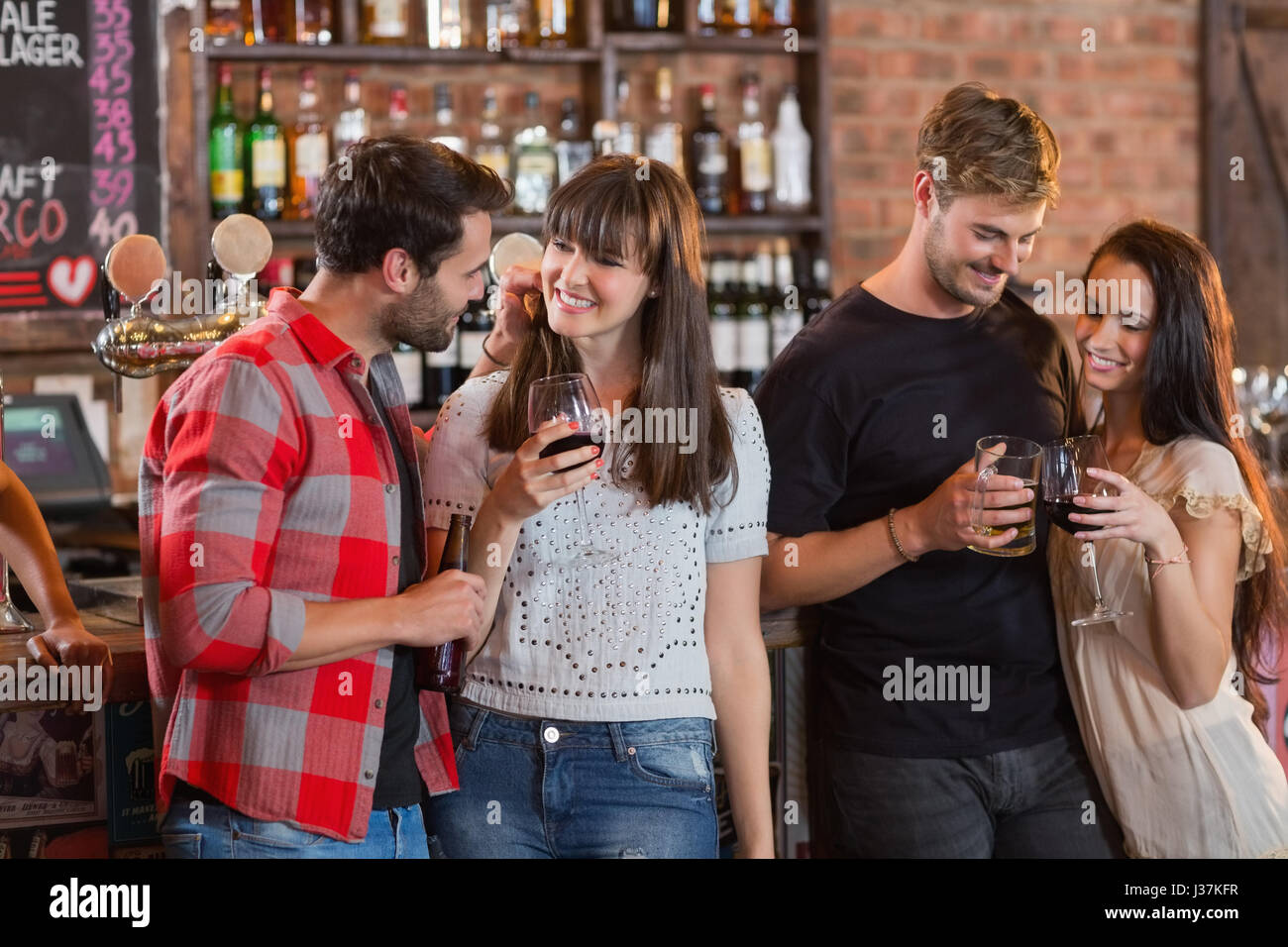 Junge Paare halten Getränke stehen in der Bar Stockfoto