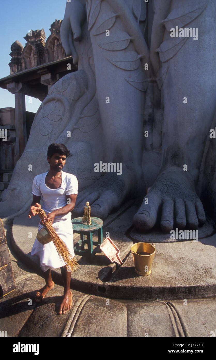 Vergleichen Sie die Füße: ein Wächter steht vor Gommateshwara, einem monolithischen Statue von Bahubali an der Jain-Schrein von Shravanabelagola, Karnataka, Indien. Stockfoto