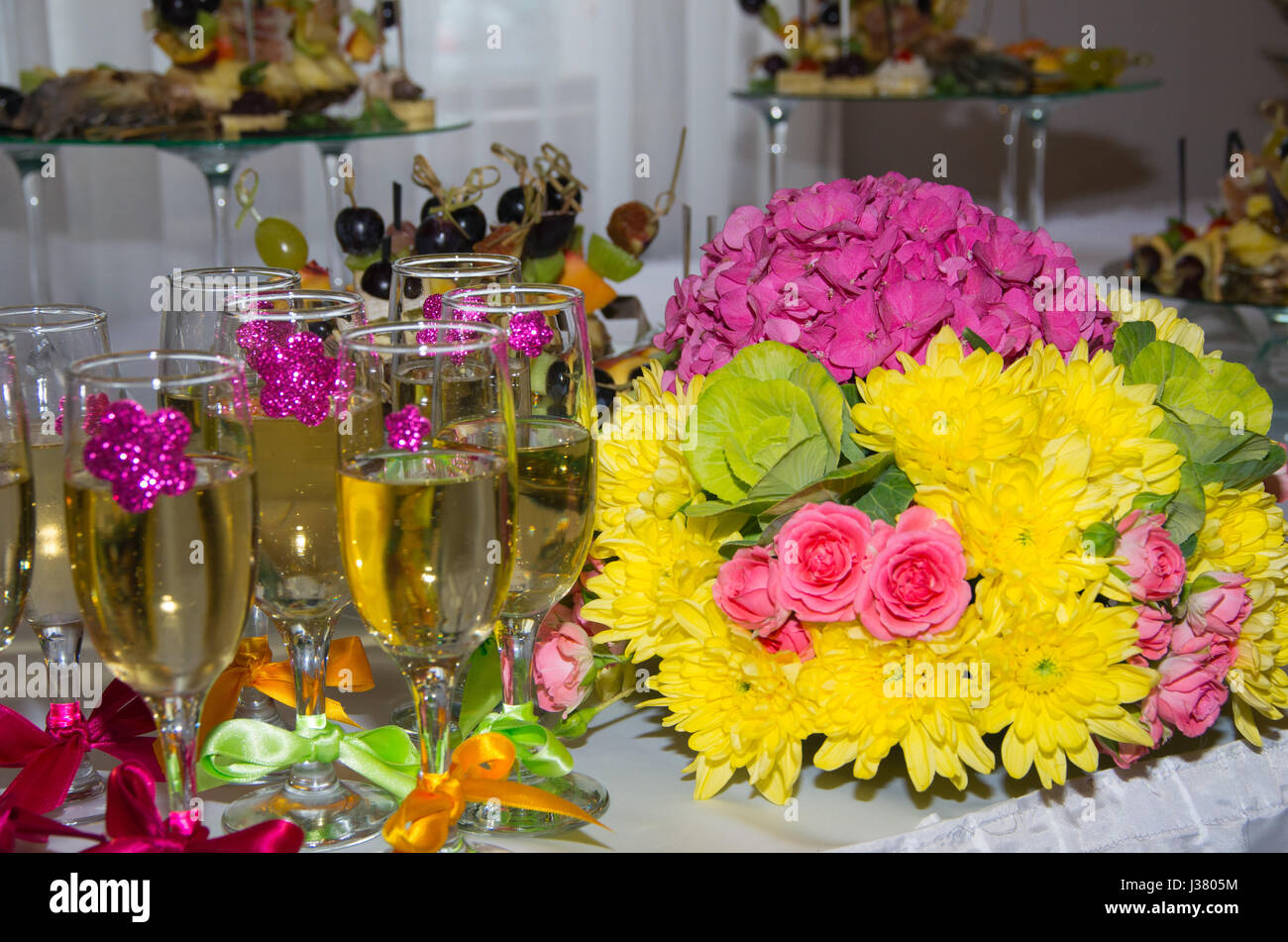 Festlich gedeckten Tisch. Glas Sekt mit Bändern geschmückt. Blumenstrauß. Frucht-snacks Stockfoto