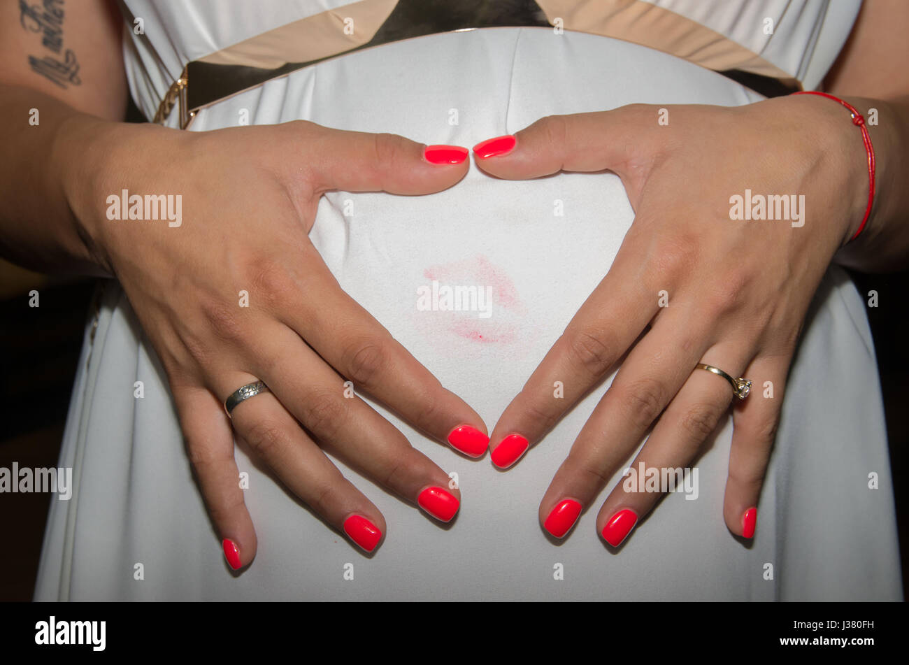 Schwangere Frau zeigt ihre Gefühle für das erwartete Kind mit Händen auf den Bauch in Form von Herzen gelegt. Stockfoto