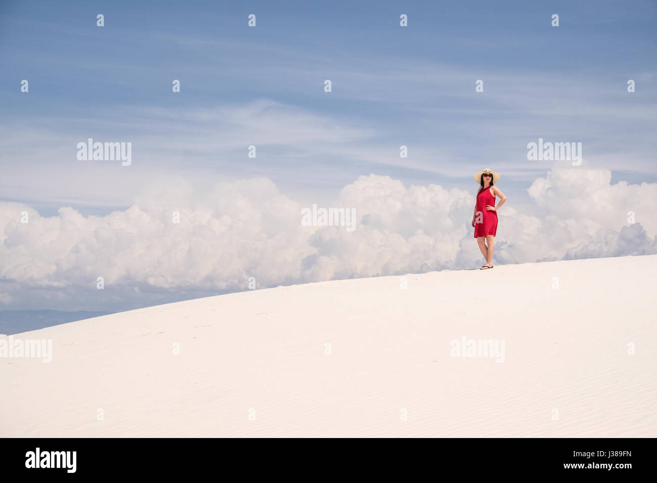 Eine asiatische Frau im roten Rock zu Fuß auf einer Sanddüne am White Sands National Monument, New Mexico, Vereinigte Staaten Stockfoto