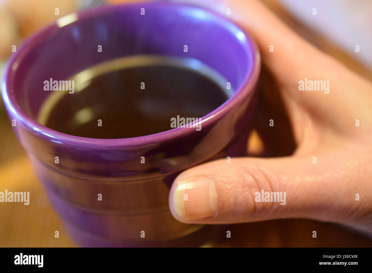 Frau Hand hält eine lila Kaffeetasse. Stockfoto