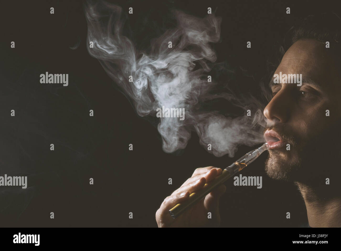 Junger Mann halten und Dampfen eine elektronische Zigarette, e-Cig, Ecigarette. Stockfoto