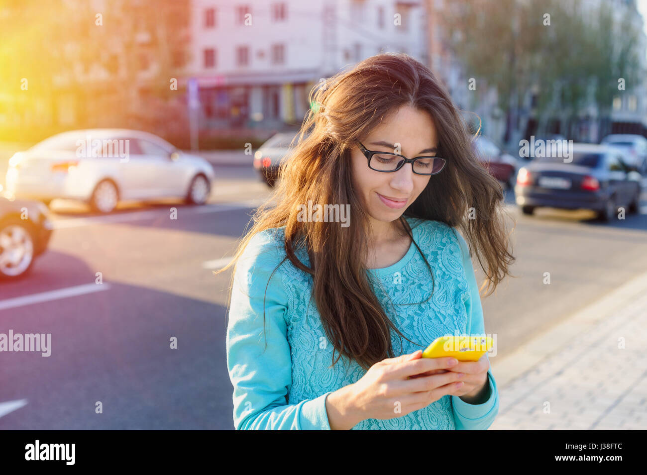 Schöne junge Frau in Gläsern mit einem Smartphone schreiben Stockfoto