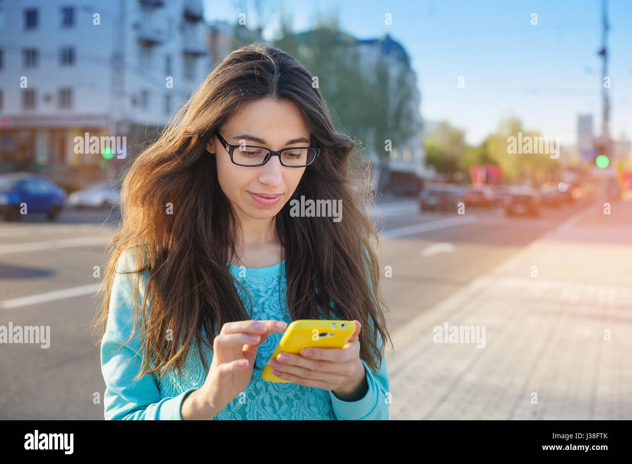 Schöne junge Frau in Gläsern mit einem Smartphone schreiben Stockfoto