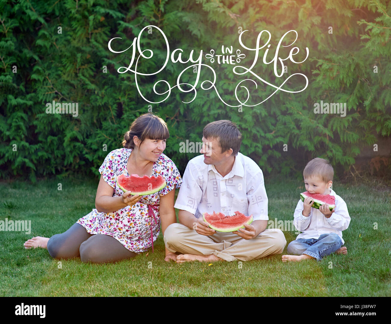 Vater, Mutter und Sohn sitzen auf dem Rasen und Text Tag im Leben Wassermelone essen. Kalligraphie Schriftzug Vintage Hand zeichnen Stockfoto