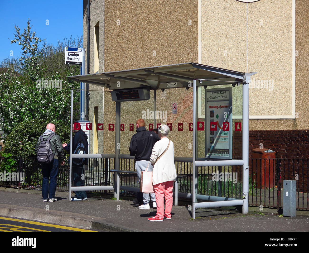 Menschen warten an der Bushaltestelle in Possilpark Glasgow Stockfoto