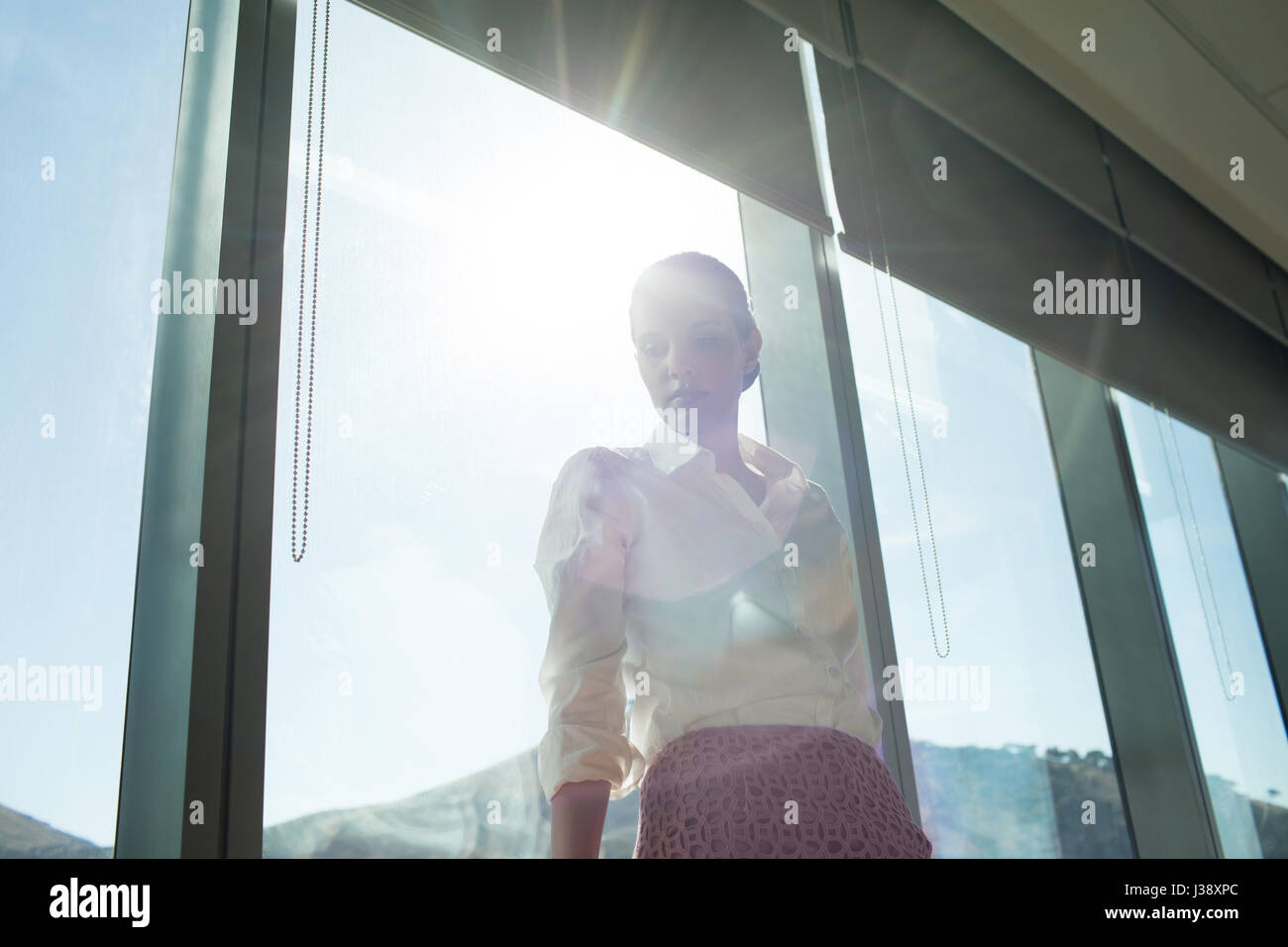 Niedrigen Winkel Ansicht der Geschäftsfrau, die hell erleuchteten Fenster im Büro stand Stockfoto