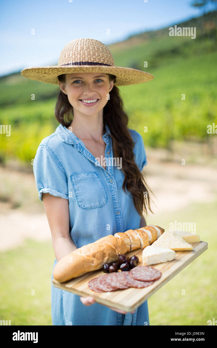 Porträt der Frau hält Brot mit Käse und Fleisch auf Holztablett im Feld Stockfoto