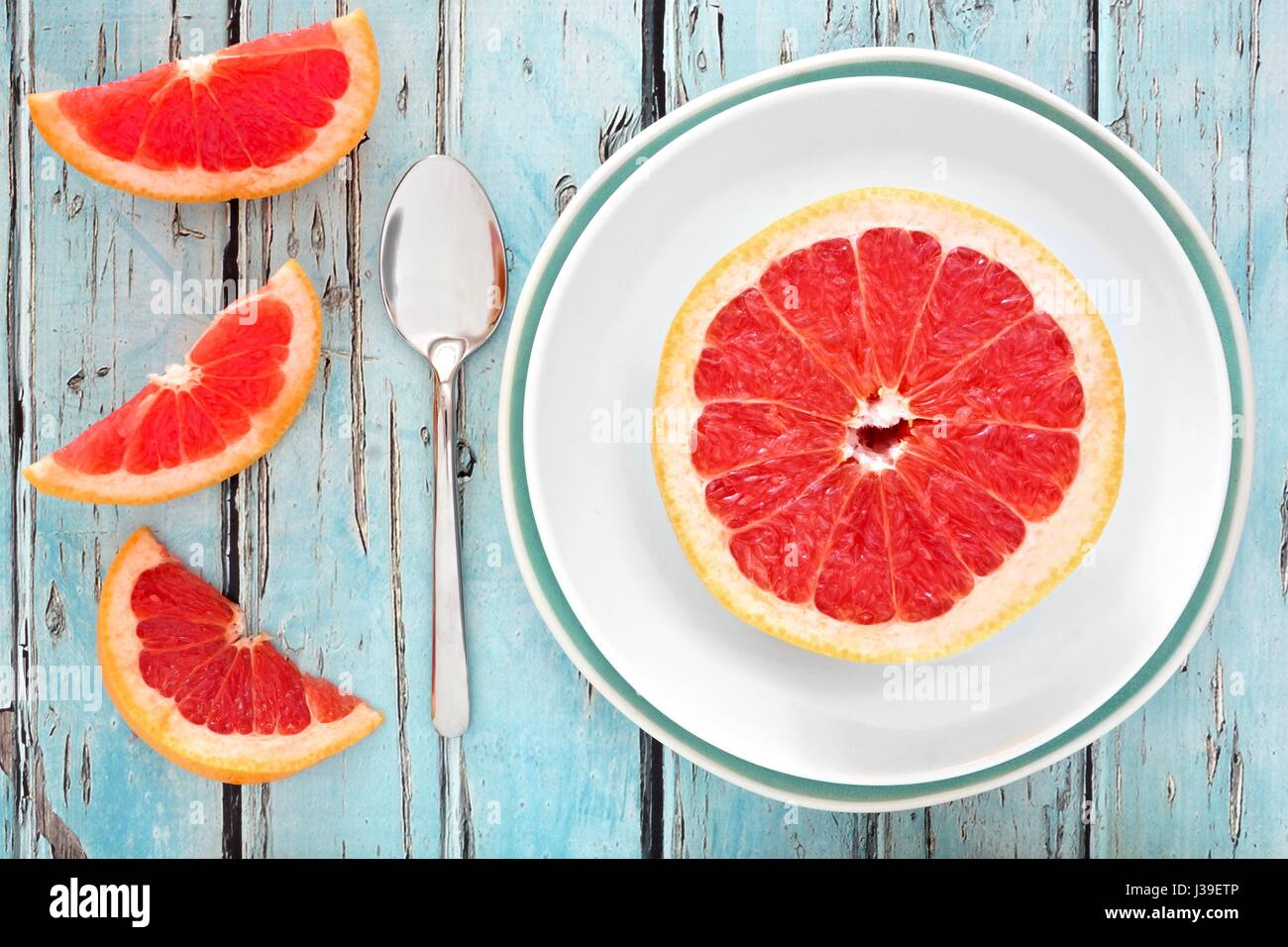 Frische rosa Grapefruit Scheiben auf Teller mit rustikalen hölzernen Hintergrund Stockfoto