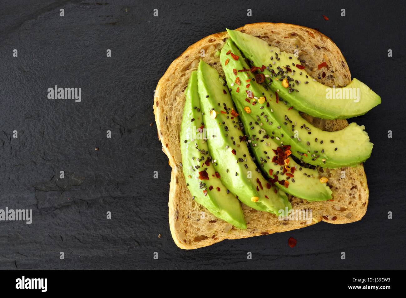 Offenen Avocado Sandwich mit Chiasamen auf Vollkornbrot vor einem dunklen Hintergrund Schiefer Stockfoto