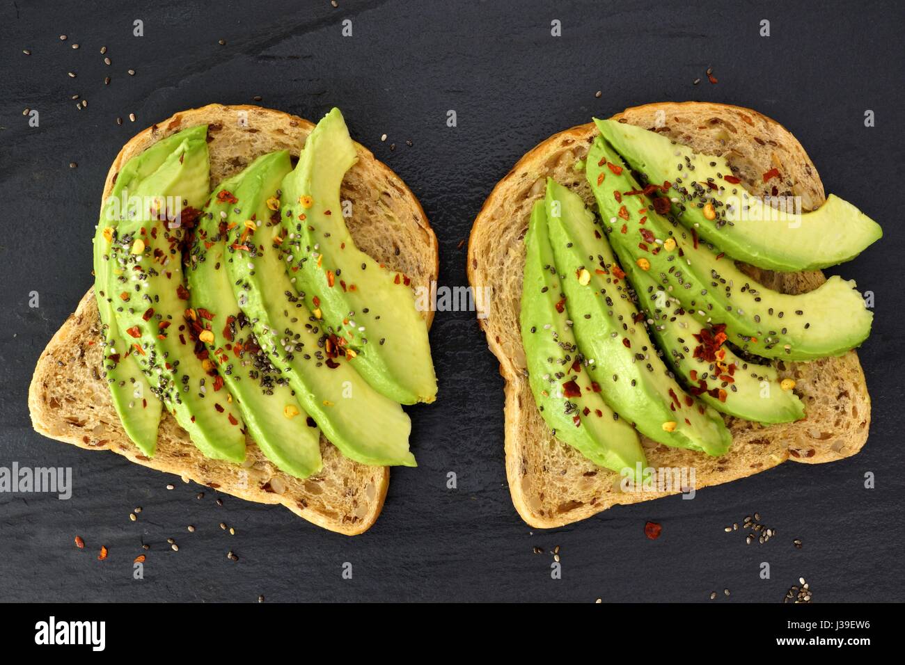 Offenen Avocado-Sandwiches mit Chia-Samen auf Vollkornbrot vor einem dunklen Hintergrund Schiefer Stockfoto