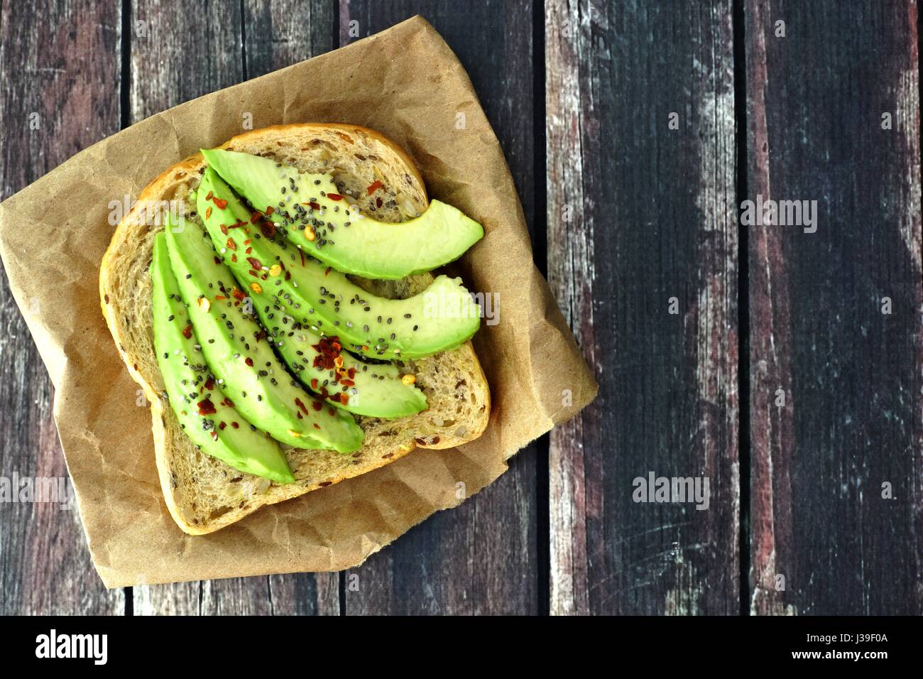 Offenen Avocado Sandwich mit Vollkornbrot auf Papier vor einem rustikalen hölzernen Hintergrund Stockfoto