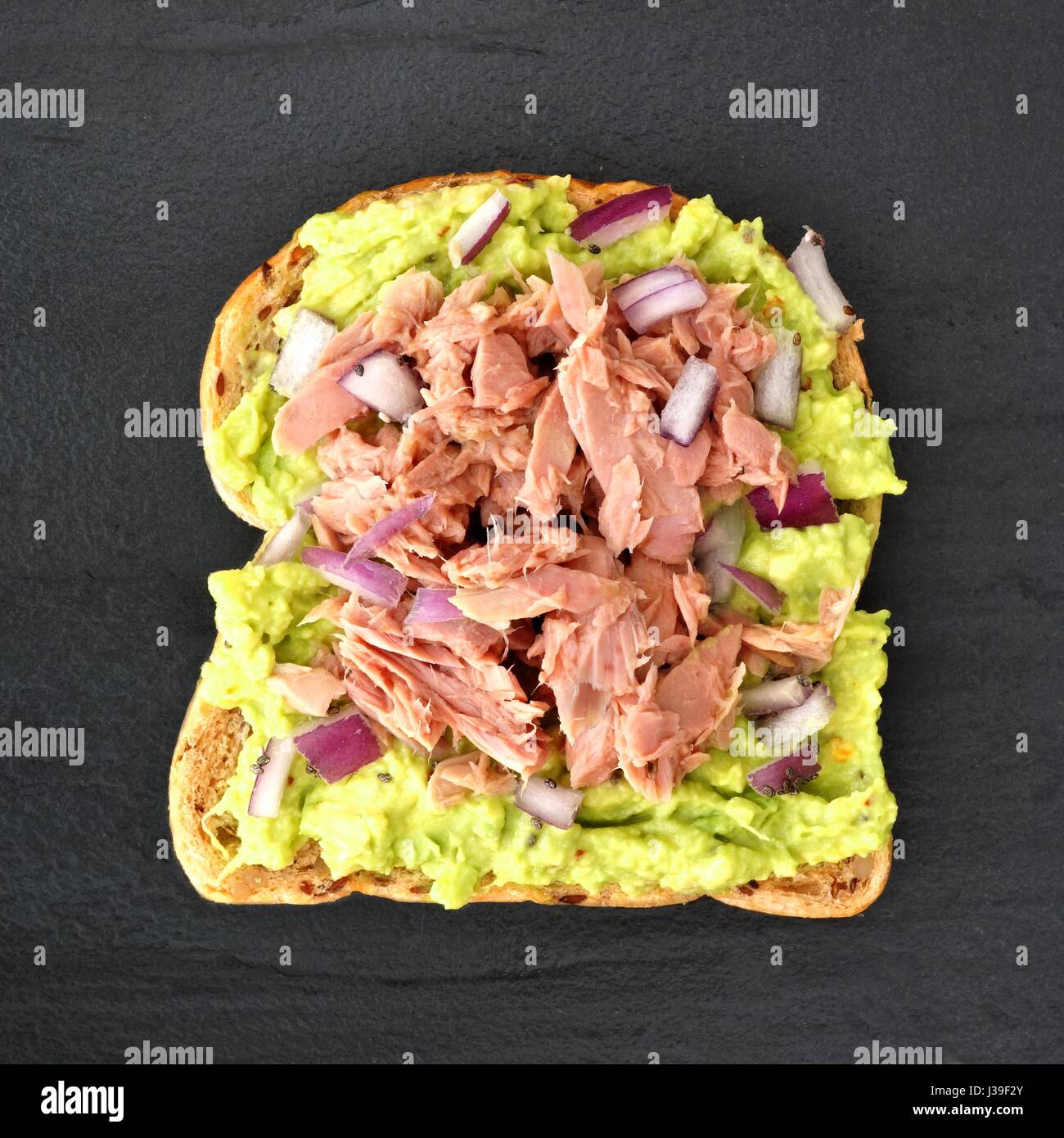 Offenen Avocado Sandwich mit Thunfisch, Brot rote Zwiebel und Chia Samen auf Vollkorn vor einem dunklen Hintergrund Schiefer Stockfoto