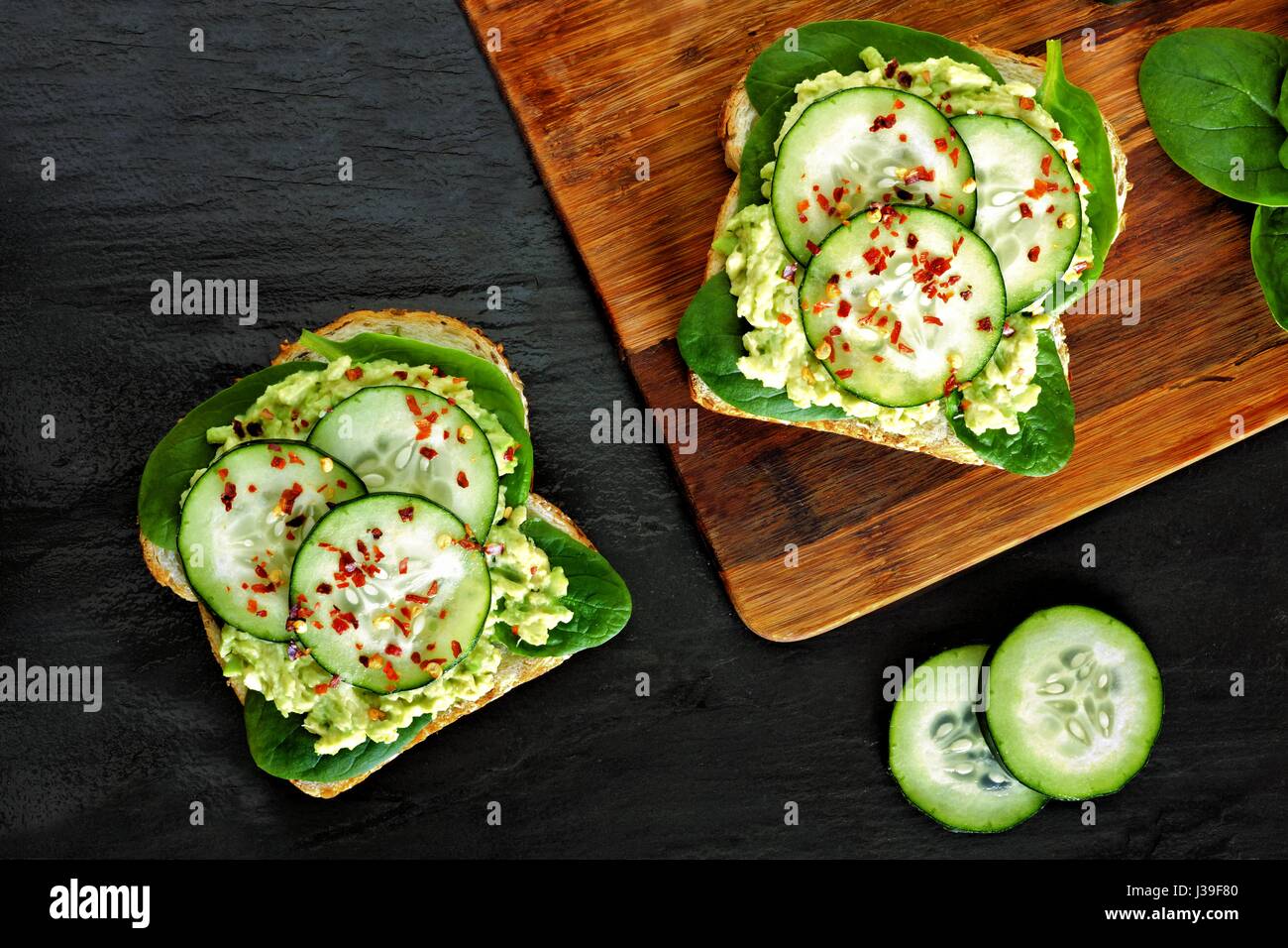Zwei Avocado-Toast-Sandwiches mit Gurken und Spinat auf Vollkornbrot Stockfoto
