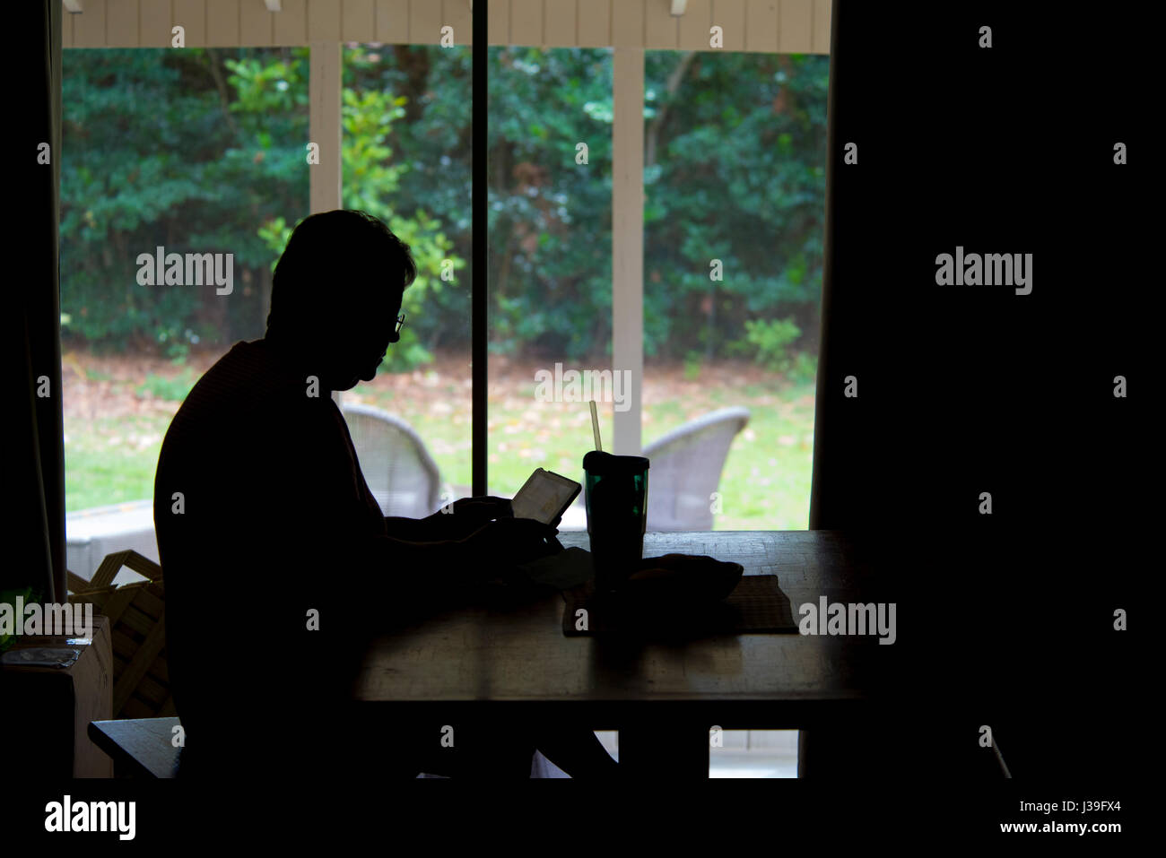 Silhouette der Dame am Tisch mit iPad oder Laptop arbeiten Stockfoto
