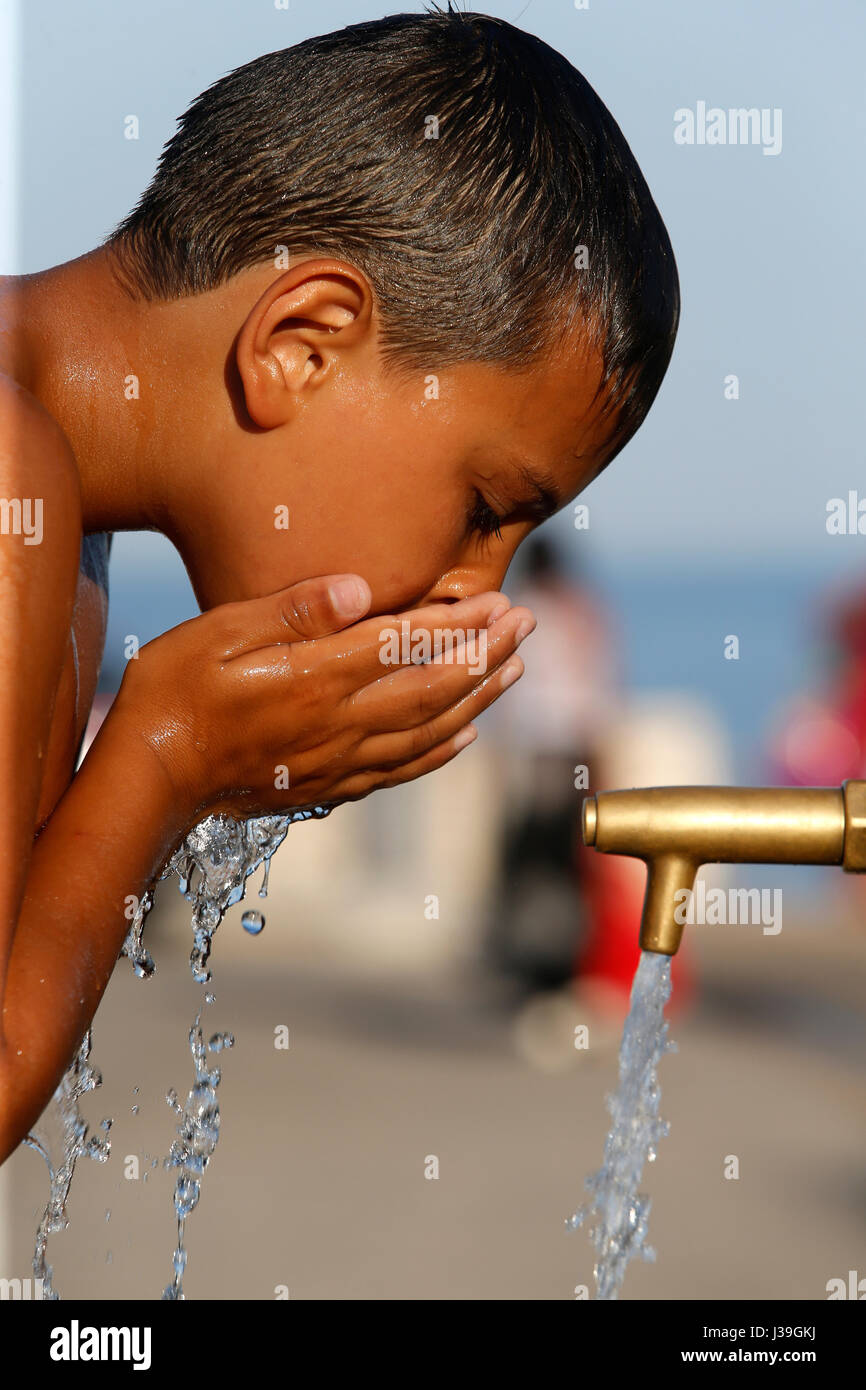 Junge Trinkwasser aus einem Brunnen. Stockfoto