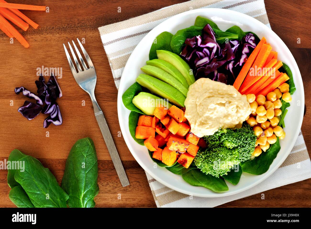 Gesundes Mittagessen Schüssel mit Avocado, Hummus und frisches Gemüse, obenliegende Szene auf Holztisch Stockfoto