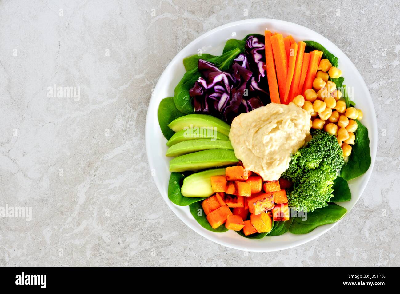Gesundes Mittagessen Schüssel mit frischem Gemüse und Hummus, Draufsicht auf weißem Marmor Stockfoto