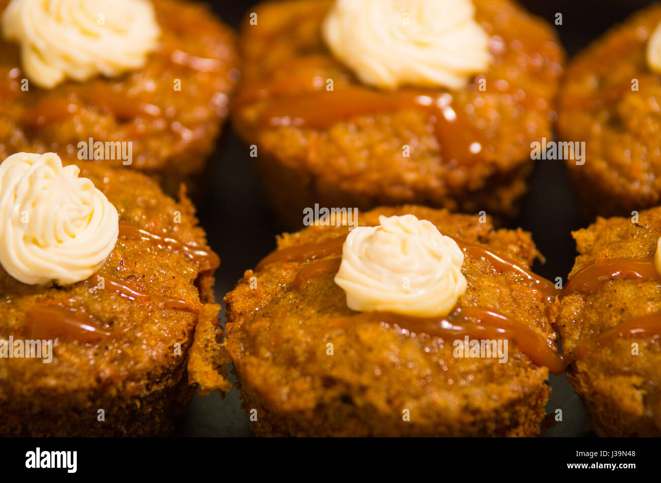 Leckeren braunen farbigen Muffins mit Karamell und Sahne-Topping, aufgereiht, wie von oben Winkel, Gebäck Konzept gesehen Stockfoto