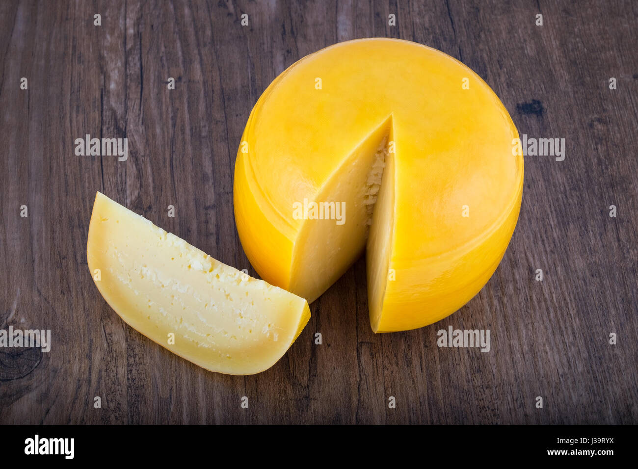 Käse-Kopf mit einer Scheibe abschneiden auf Holztisch Stockfoto