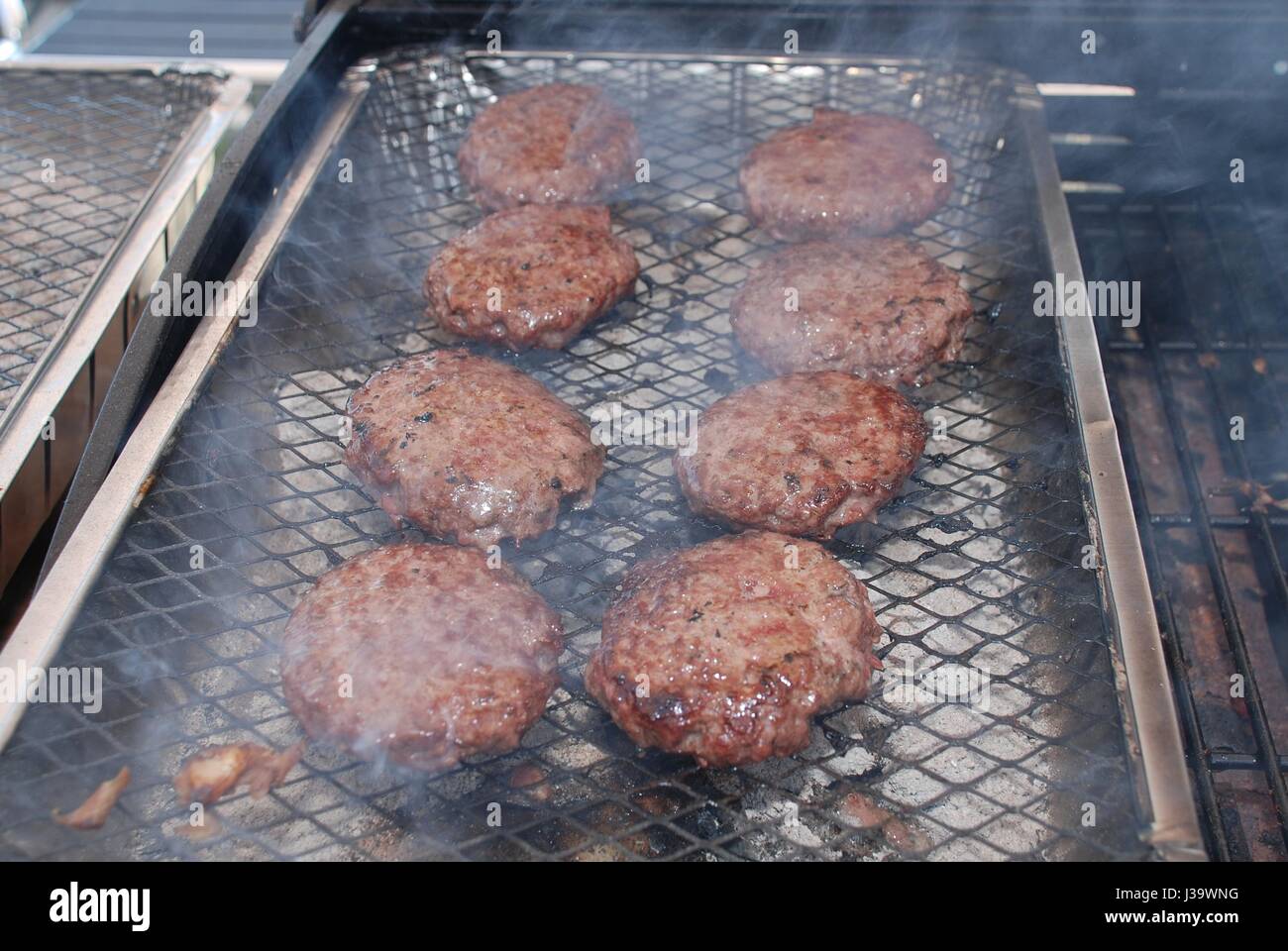 Burger Kochen auf einen Einweg-Grill in der Summer.in der UK Stockfoto