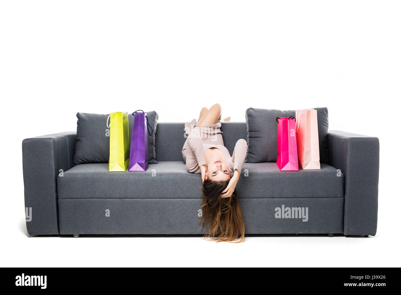 Frau sitzt auf der Couch mit vielen Shopping-Bag um Schauspielerei glücklich mit Armen weit gespreizt Stockfoto