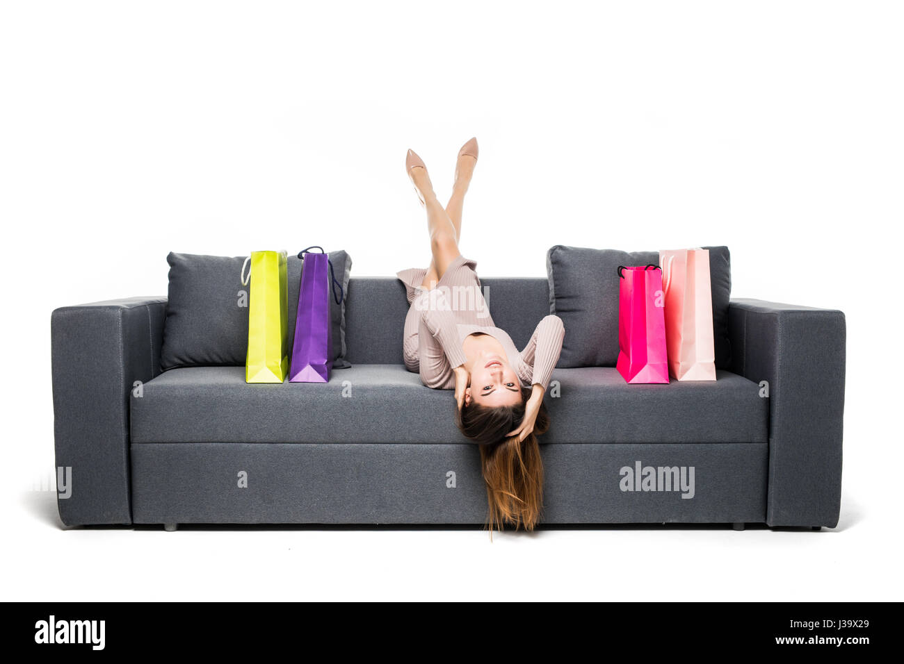 Frau sitzt auf der Couch mit vielen Shopping-Bag um Schauspielerei glücklich mit Armen weit gespreizt Stockfoto
