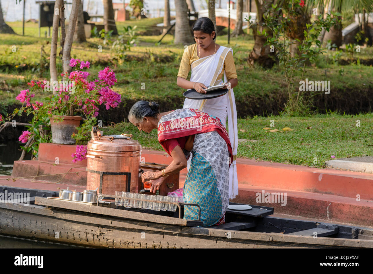 Keralas Frauen in Saris bereiten Sie Tee auf einem Boot für Gäste im Coconut Lagoon Resort, Kottayam, Kavanattinkara, Kumarakom, Kerala, Süd-Indien, Südasien Stockfoto