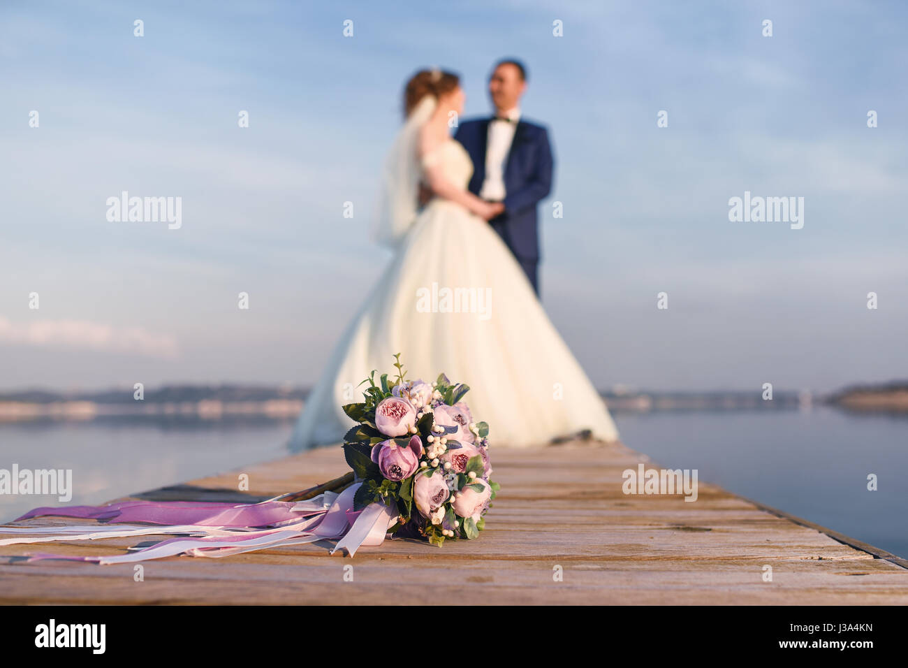 Junges Paar in Liebe Braut und Bräutigam mit einem Blumenstrauß posiert auf einem Hintergrund-pier Stockfoto