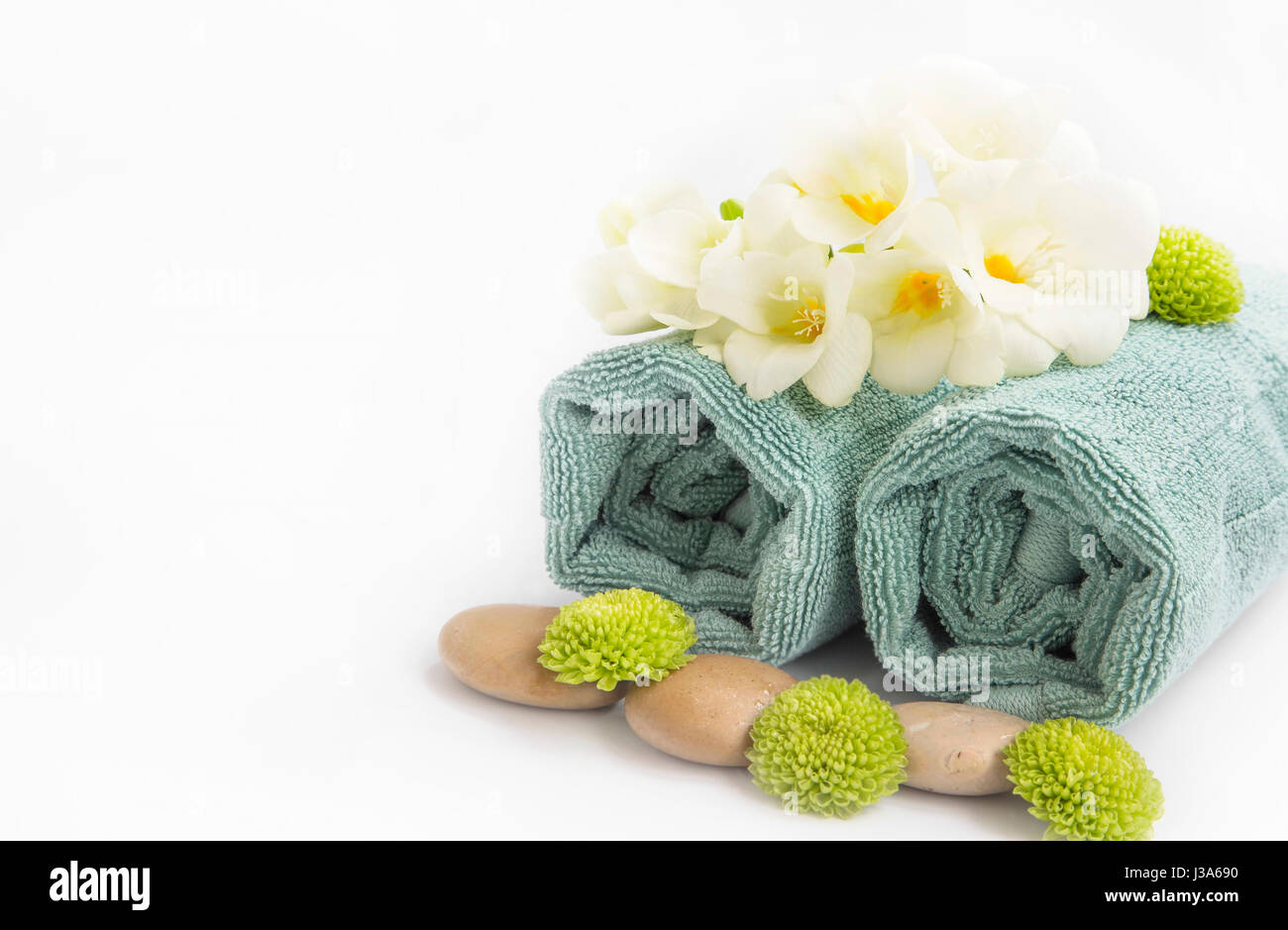 Spa-Stillleben-Einstellung mit Handtüchern, massage, Steinen und Blumen, isoliert auf weiss mit Textfreiraum Stockfoto