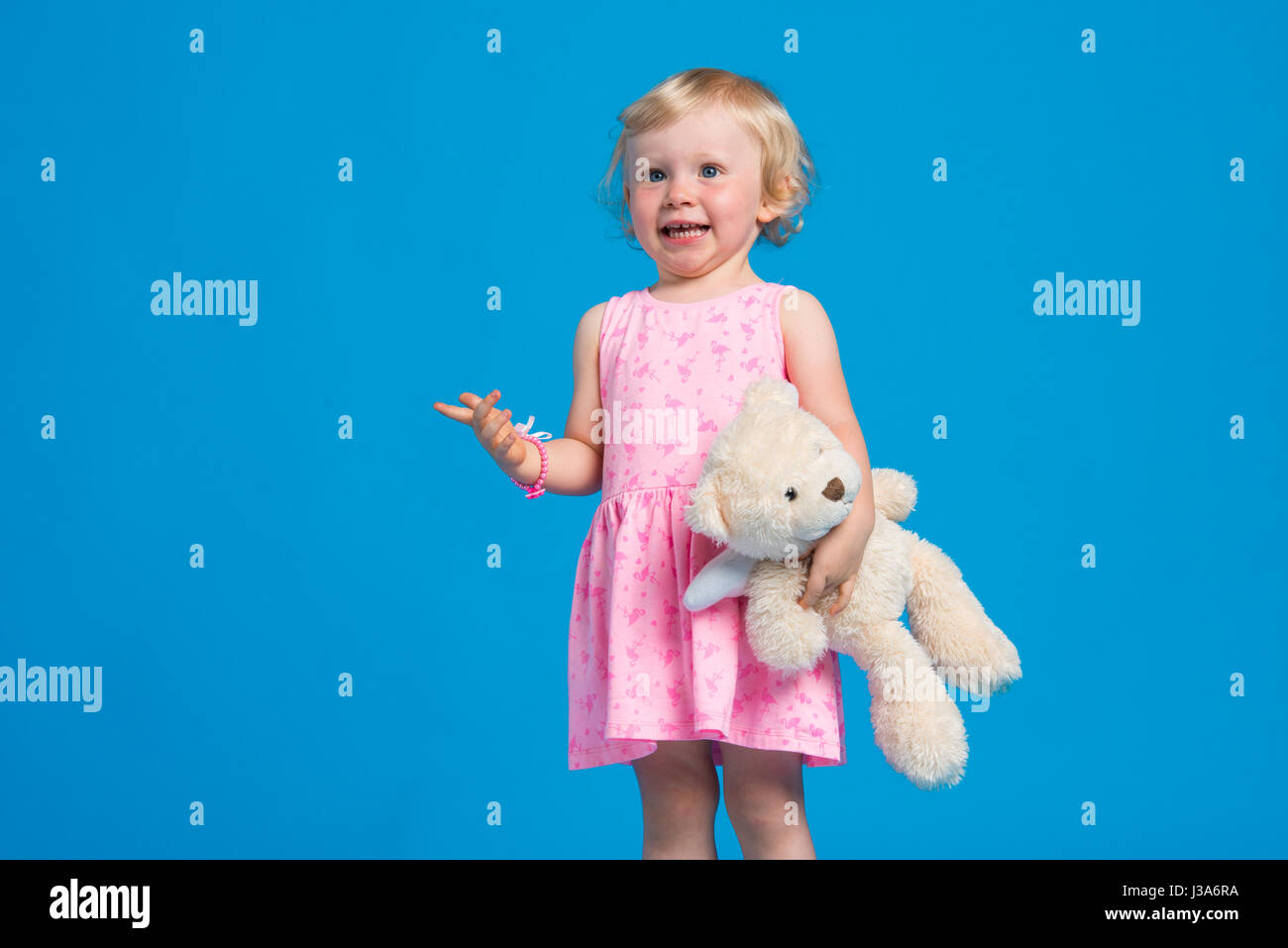 Portrait von schönen jungen Mädchen in rosa Kleid vor blauem Hintergrund Stockfoto