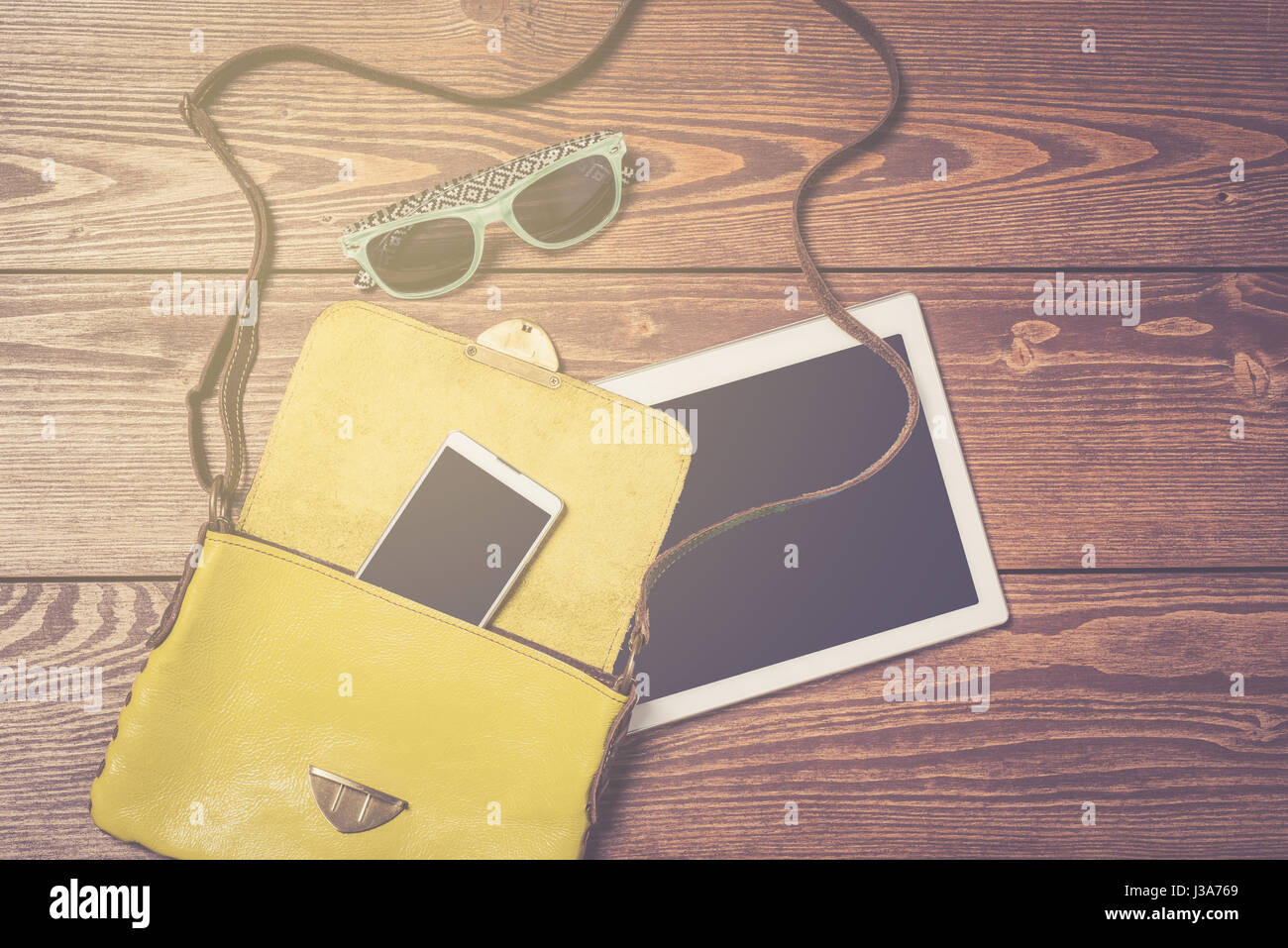 Weibliche Tasche mit weißen Smart Phone und Tablet auf hölzernen Tisch Stockfoto