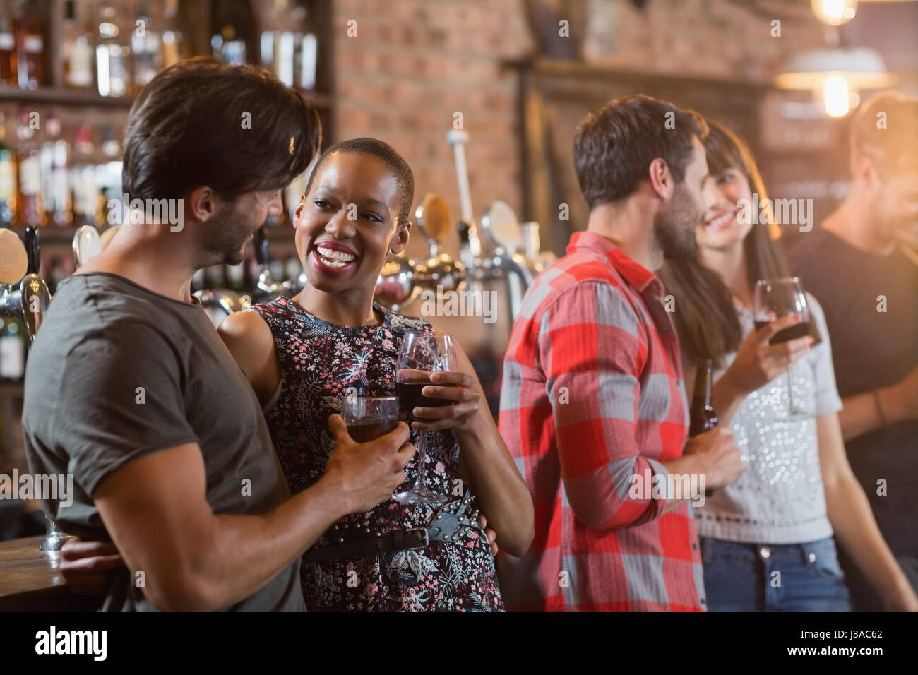 Glückliche Paare halten Getränke in der Bar Stockfoto