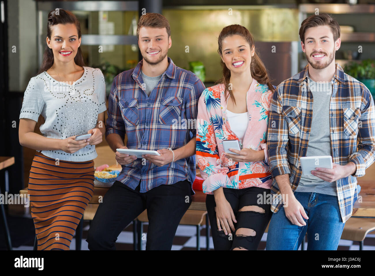 Porträt von Freunden posiert mit Handys und digitalen Tablets im restaurant Stockfoto