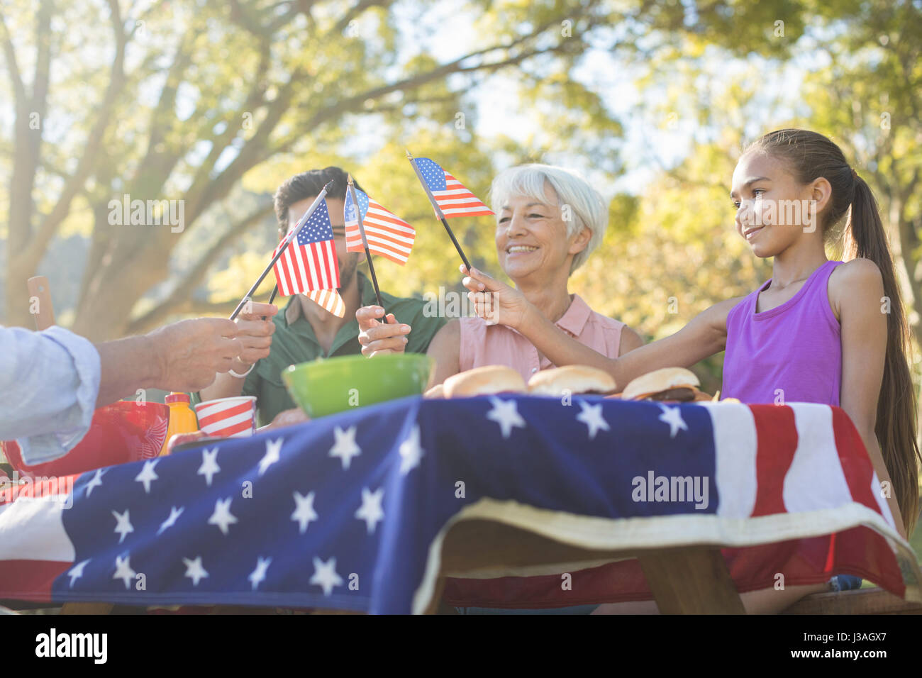 Glückliche Familie halten amerikanische Flaggen und mit Essen im park Stockfoto